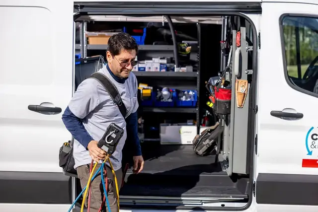 Champion and Nash technician stepping out of a fully stocked service van with manifold gauges in hand, company decal on the door